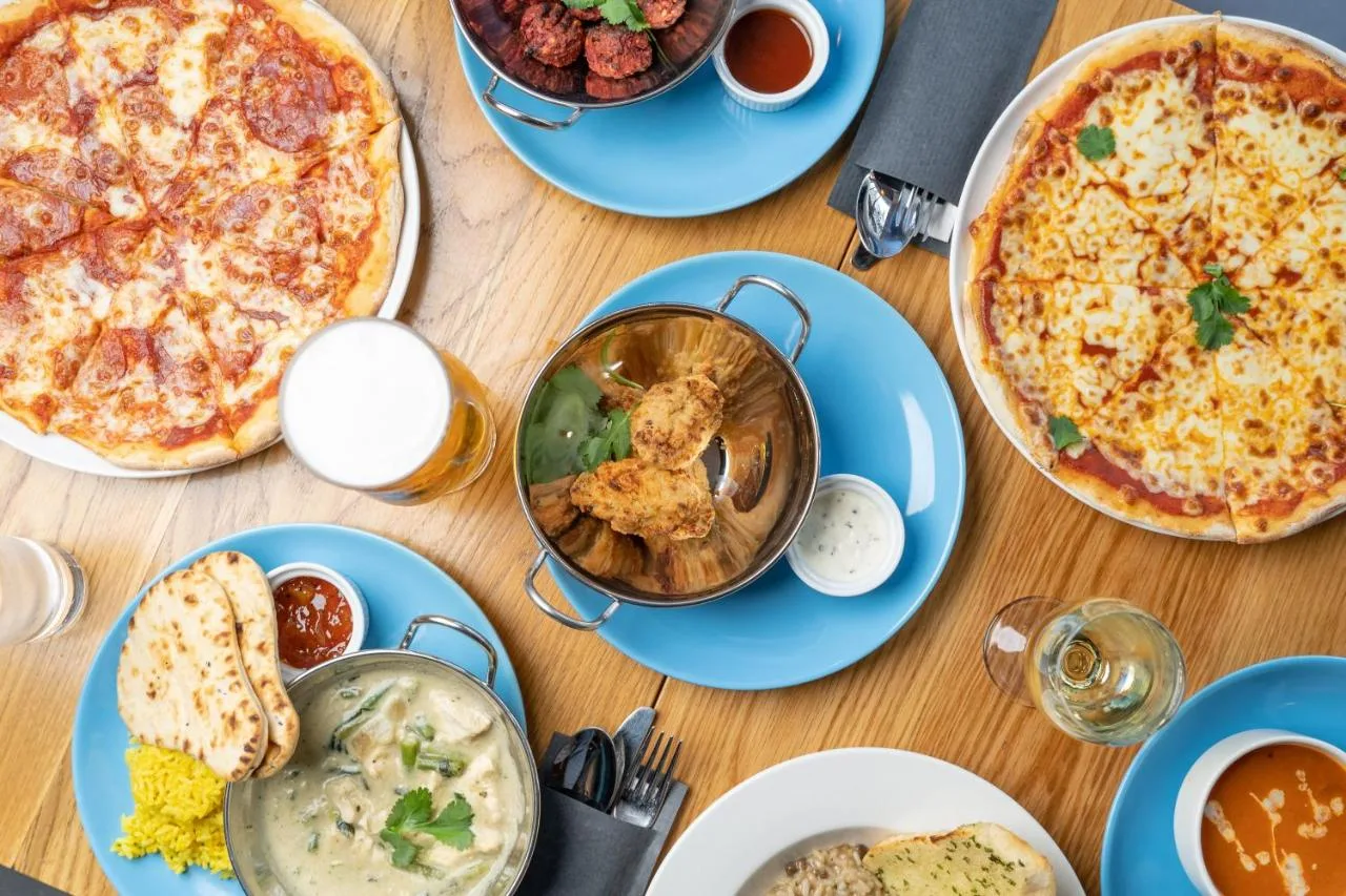 a table filled with plates of food with pizza at Holiday Inn Express Aberdeen City Centre by IHG in Aberdeen