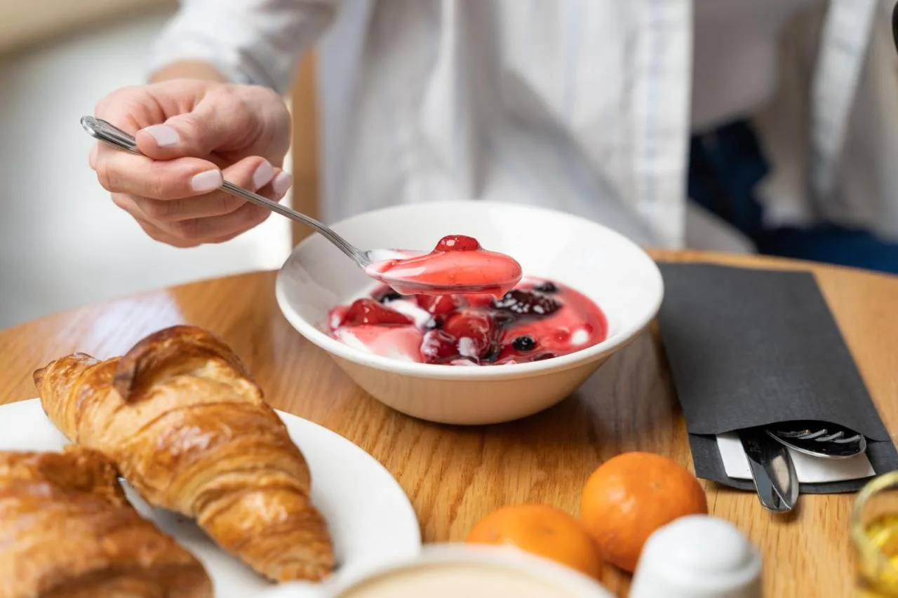 a person eating a bowl of fruit and croissants on a table at Holiday Inn Express Aberdeen City Centre by IHG in Aberdeen